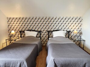A double room with two beds, each with a headboard and nightstand, against a patterned wall. - Cozy house, private parking - 6 guests (Méteren)