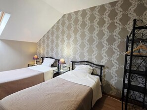 Une chambre d’hôtel avec deux lits, une table de chevet avec une lampe, une armoire et un mur décoré d’un motif.