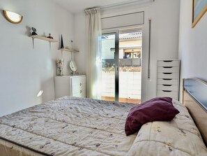 A bedroom with a bed, a dresser, a mirror, and a window with a view of buildings. - Cozy apartment near center - 5 guests (Tossa de Mar)