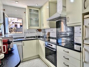 A modern kitchen with white cabinets, a black countertop, and a built-in oven. - Cozy apartment near center - 5 guests (Tossa de Mar)