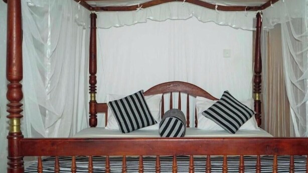 A four-poster canopy bed with a wooden frame and white drapes. - Goyambokka Beach Retreat (Tangalle)