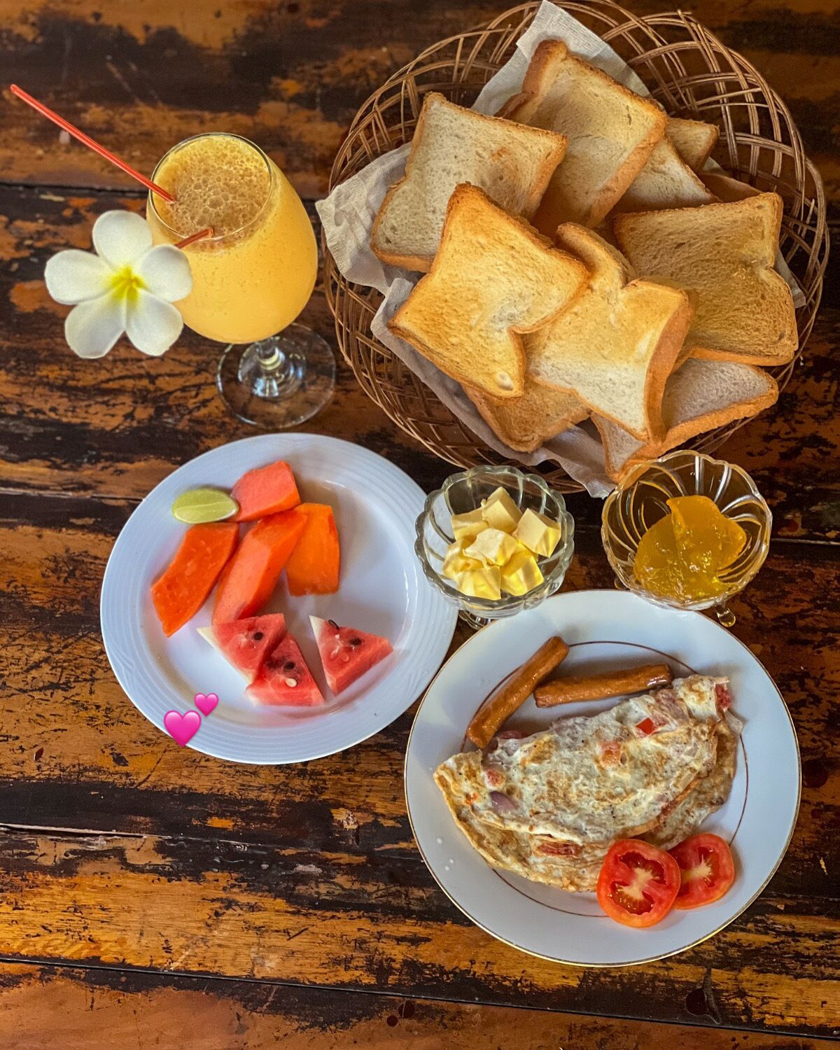 Un repas composé de pain grillé, de pastèque, de fromage et d’une omelette, servi sur une table en bois.