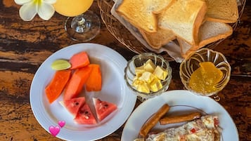 Un repas composé de pain grillé, de pastèque, de fromage et d’une omelette, servi sur une table en bois.
