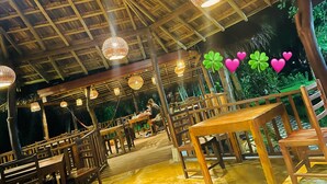 An indoor dining area with wooden tables and chairs, hanging light fixtures, and a thatched roof ceiling. - Goyambokka Beach Retreat (Tangalle)