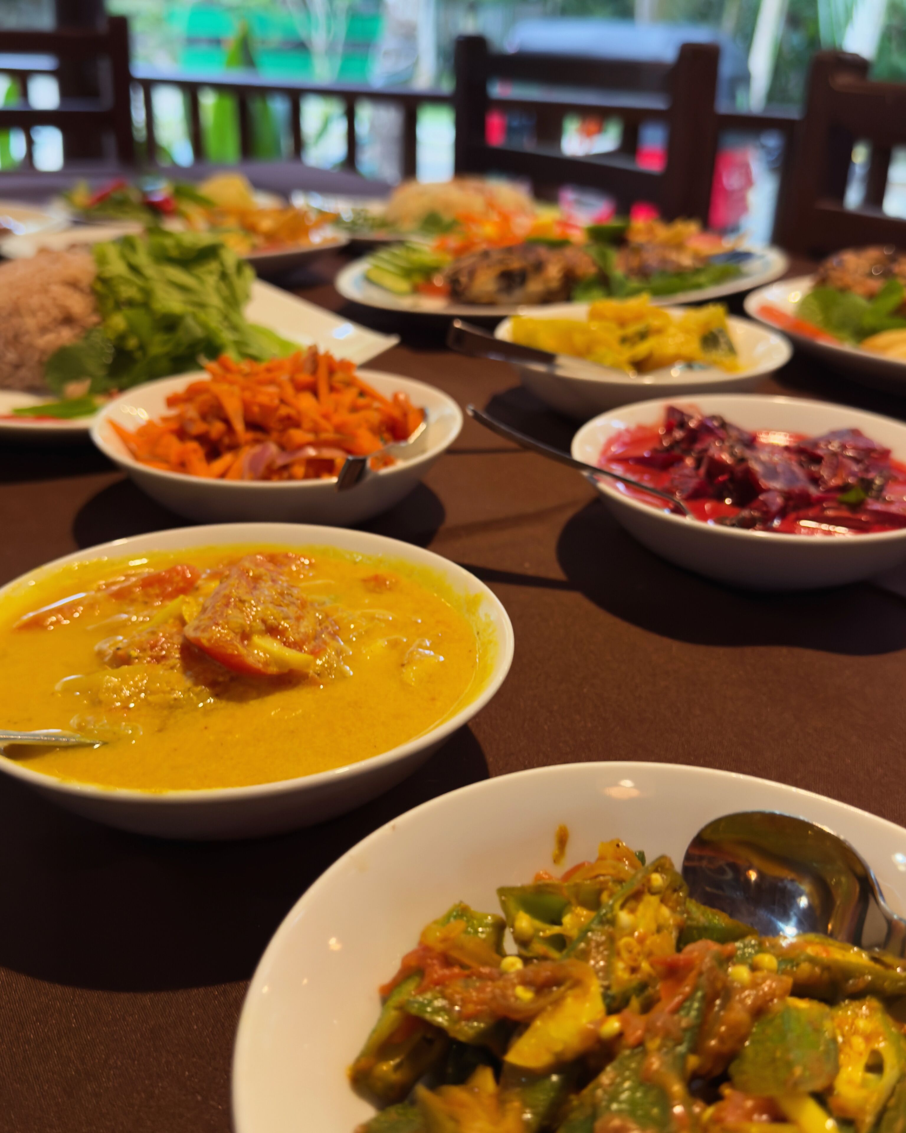 Une table à manger avec différents plats, notamment un bol de soupe, une assiette de légumes et d’autres aliments.