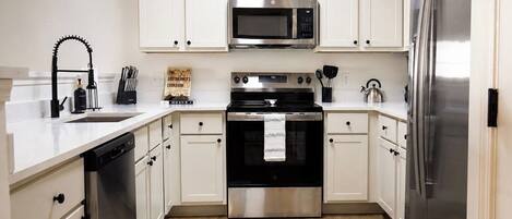 A modern kitchen with white cabinets, stainless steel appliances, and a dishwasher.