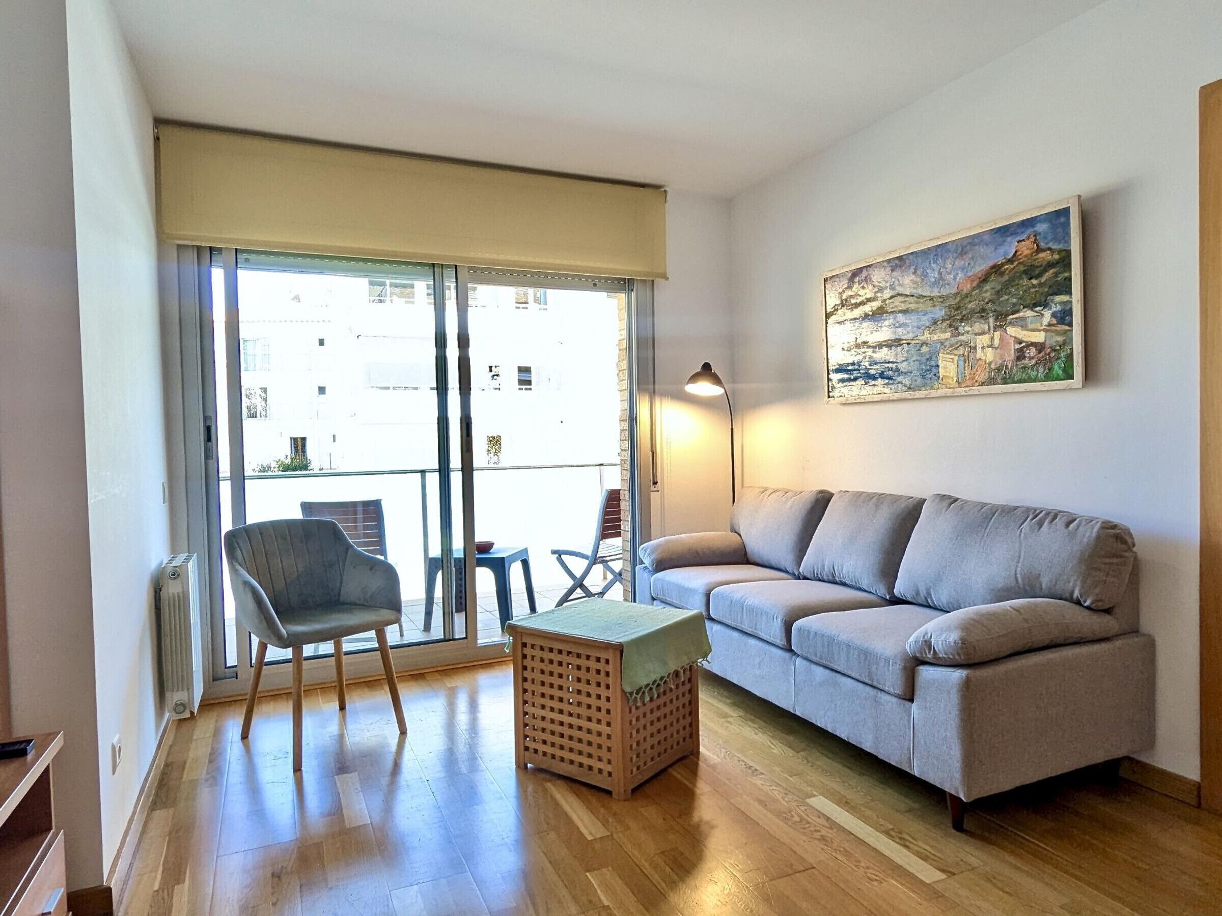 A living room with a sofa, a chair, a small table, and a painting on the wall.