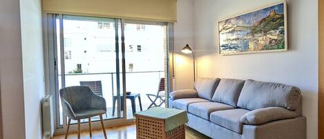 Ein Wohnzimmer mit einer Couch, einem Sessel, einem kleinen Tisch und einem Gemälde an der Wand.