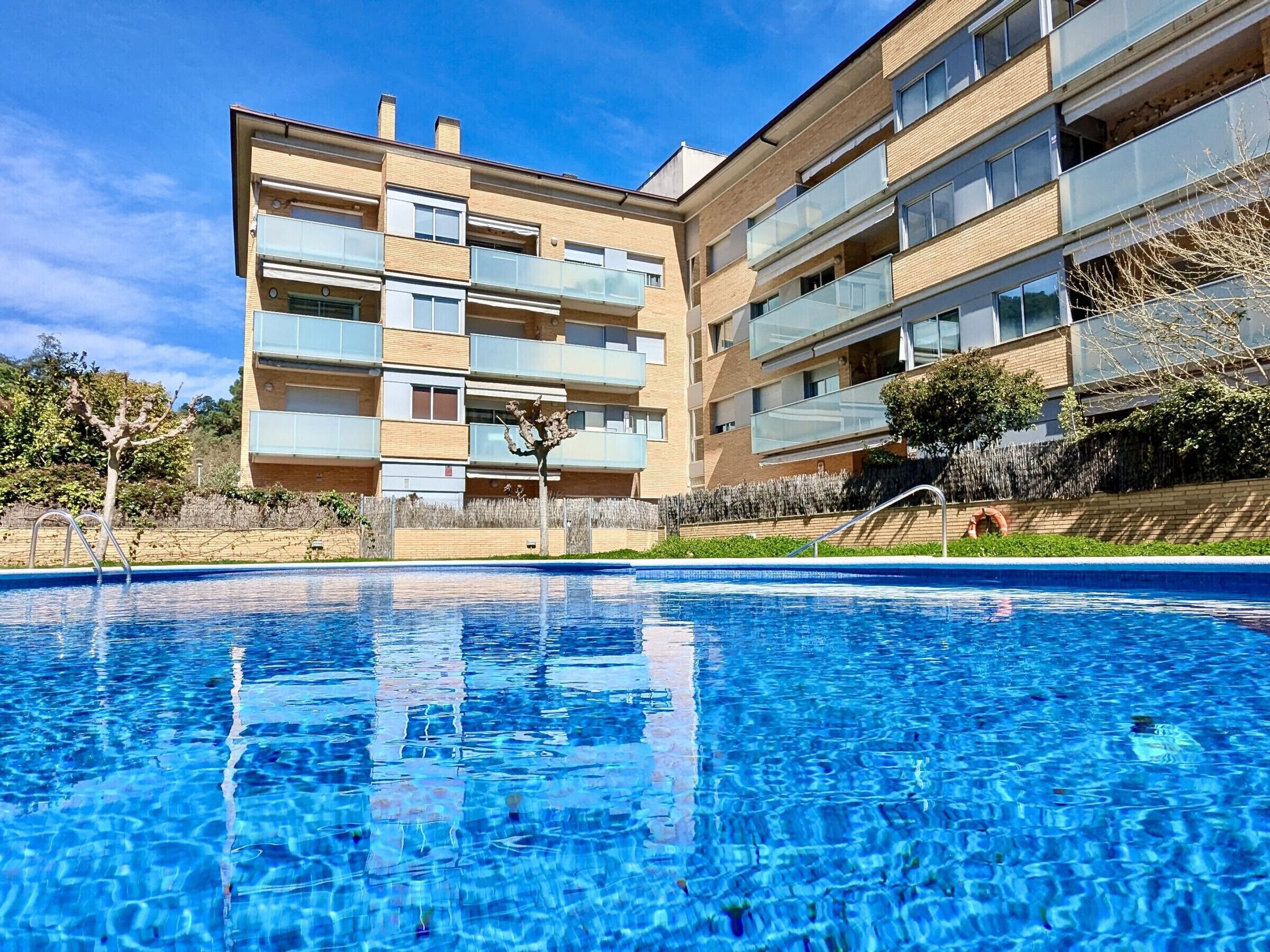 En modern lägenhetsbyggnad med en pool framför.