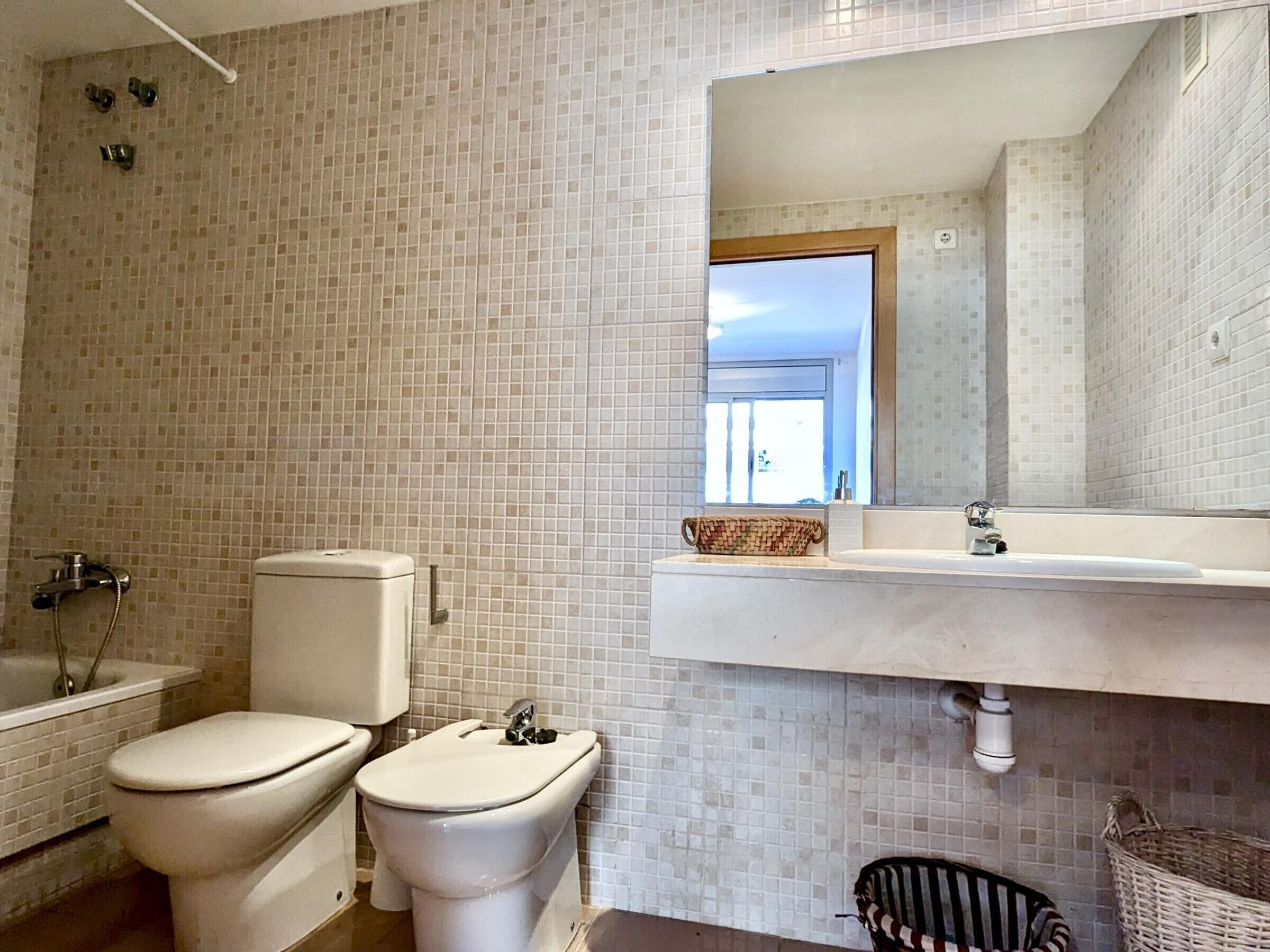 Une salle de bain avec deux toilettes, une baignoire, un lavabo et un miroir.