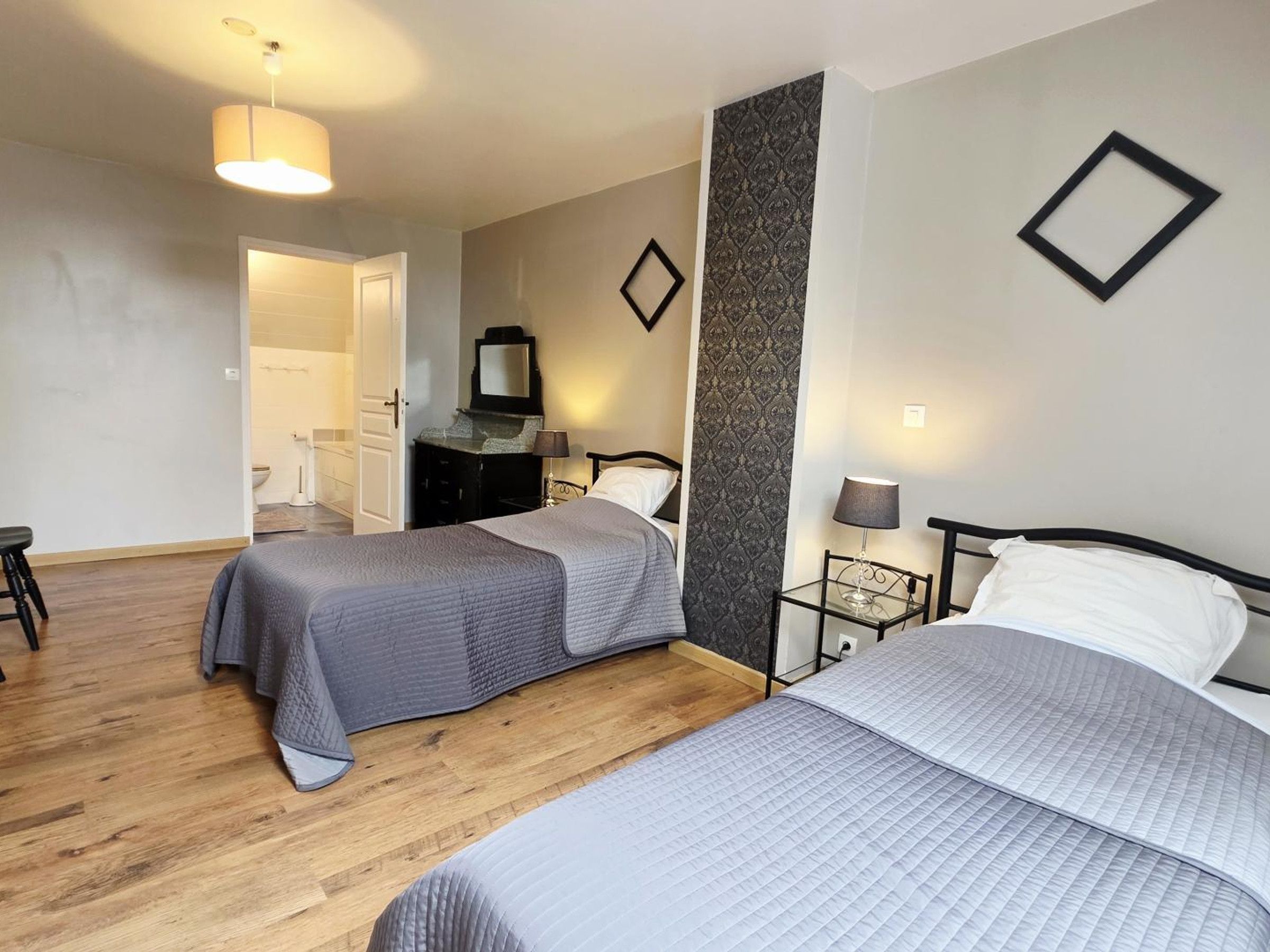 Une chambre d’hôtel avec deux lits, une commode, un miroir, une table de chevet et une lampe.
