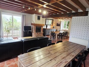 Un comedor con mesa y sillas de madera, chimenea de ladrillo y vistas al exterior.