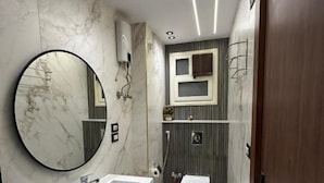 A modern bathroom with a rectangular sink, a round mirror, a toilet, and a shower area. - city plaza pyramid view (Giza)