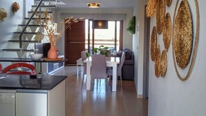 Una cocina moderna con comedor, una escalera y una sala de estar con sofá y mesa de centro.