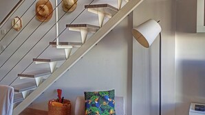 Una escalera de diseño moderno, una lámpara y un cojín estampado.