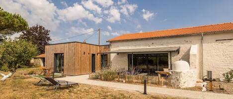 A modern house with a wooden exterior, a stone wall, and a tiled roof.