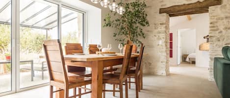 A dining area with a wooden table and chairs, a hanging light fixture, and a potted plant.