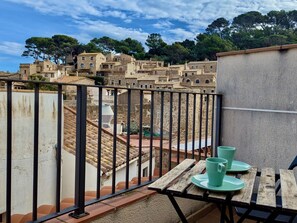 A balcony with a view of a historic town, a table with a green cup, and a railing. - Historic duplex with sea views - 6 guests (Tossa de Mar)