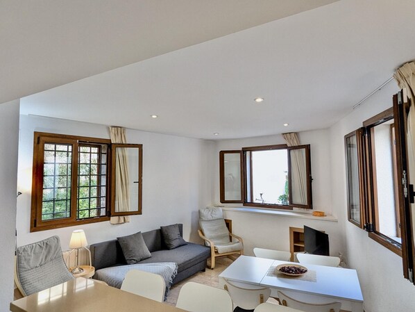 A modern living room with a sofa, chairs, a dining table, and large windows with curtains. - Comfortable apartment in the old town - 4 guests (Tossa de Mar)