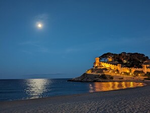 A coastal castle with a moat, illuminated by artificial lighting, overlooking a beach and the sea. - Comfortable apartment in the old town - 4 guests (Tossa de Mar)