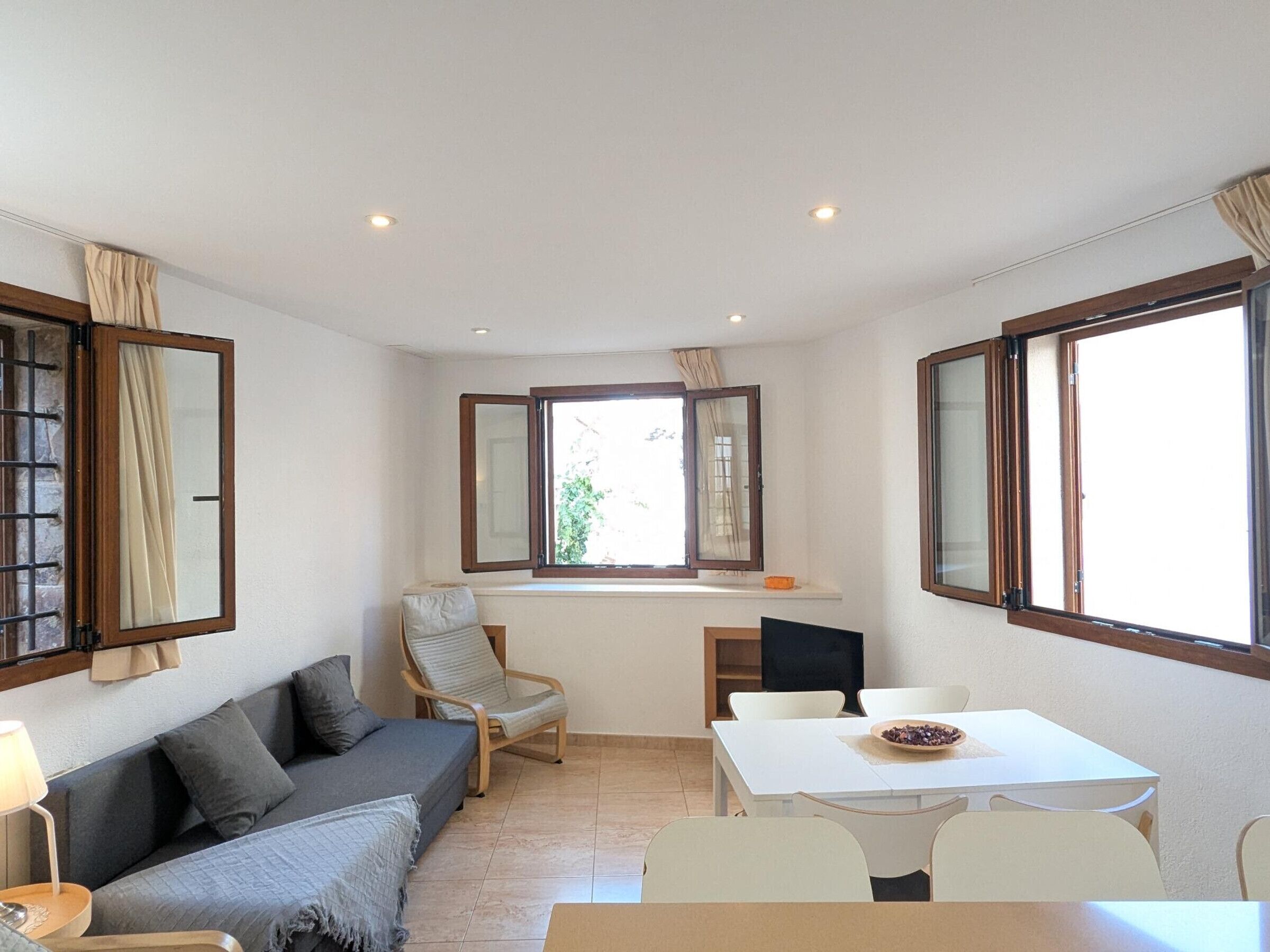 A compact living space with a sofa, a dining table, and a window with curtains.