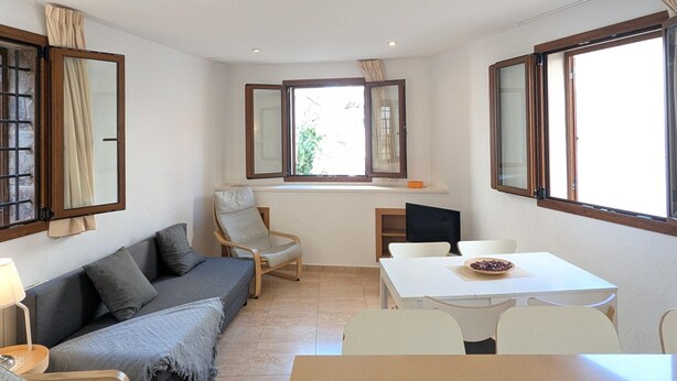 Un espacio habitable compacto con sofá, una mesa de comedor y una ventana con cortinas.