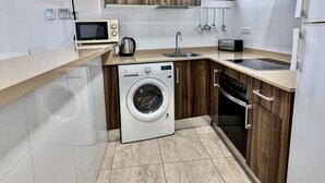 Una cocina compacta con lavadora, microondas y lavabo.