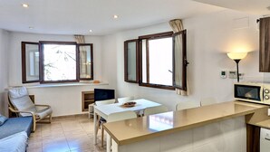 Una cocina moderna con una isla central, una zona de comedor con sillas y un sofá.