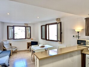 Eine moderne Küche mit einer zentralen Kochinsel, einem Essbereich mit Stühlen und einem Sofa.