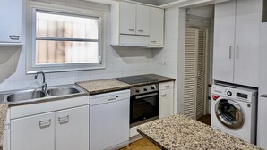 Eine kleine Küche mit Geschirrspüler, Backofen und Waschmaschine.