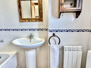 Ein Badezimmer mit einem weißen Waschbecken, einem Spiegel, einem Handtuchhalter und einer Heizung.