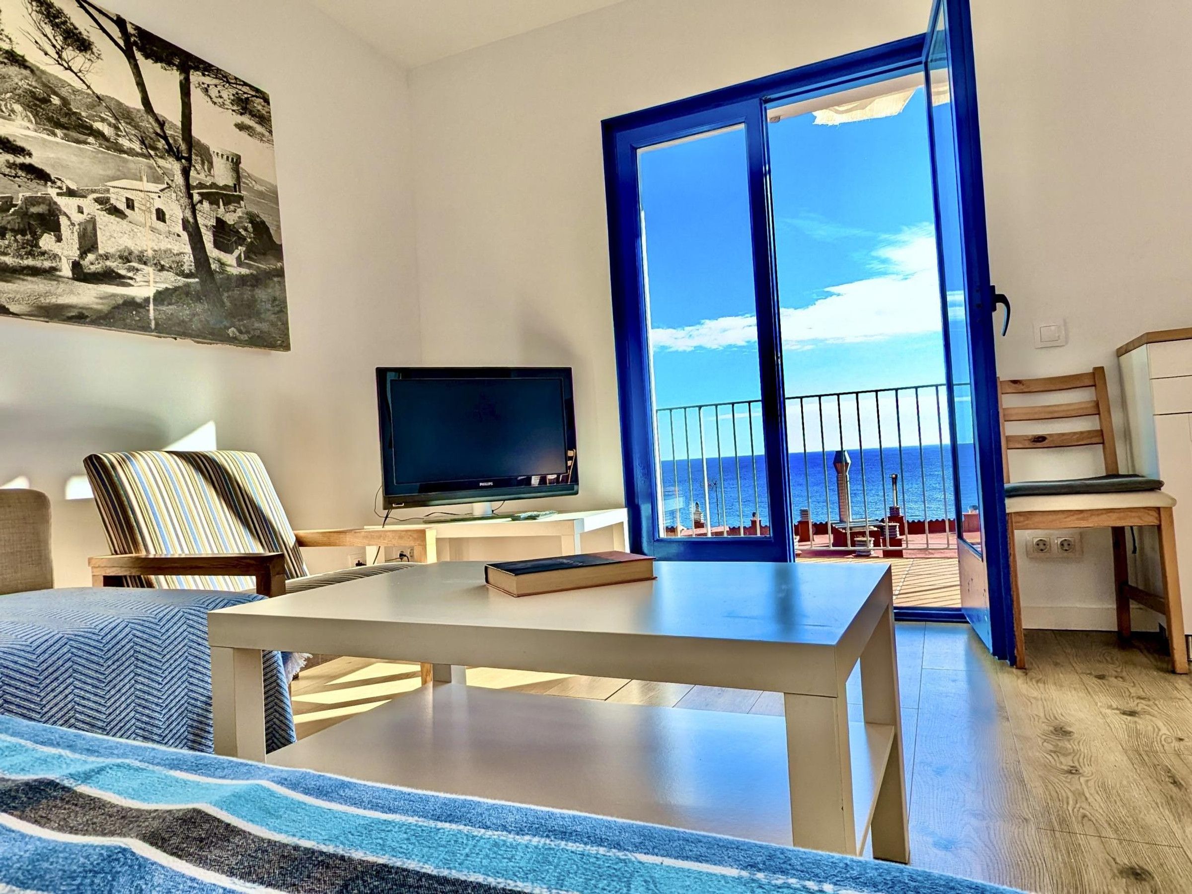 Uma sala de estar moderna com uma janela ampla, TV de tela plana, mesa de jantar e sofá.
