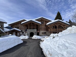 A large wooden lodge with a stone entrance, surrounded by snow. - Charming apartment at the foot of the slopes - 5 guests (Crest-Voland)