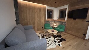 A modern living room with a grey sofa, green chairs, a small round table, and a cowhide rug. - Charming apartment at the foot of the slopes - 5 guests (Crest-Voland)