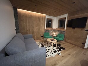 A modern living room with a grey sofa, green chairs, a small round table, and a cowhide rug. - Charming apartment at the foot of the slopes - 5 guests (Crest-Voland)