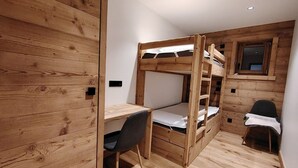 A bunk bed with a desk and chair, wooden walls, and a window. - Charming apartment at the foot of the slopes - 5 guests (Crest-Voland)
