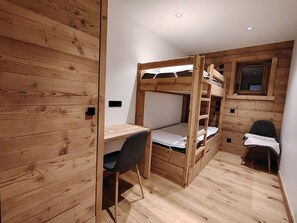 A bunk bed with a desk and chair, wooden walls, and a window. - Charming apartment at the foot of the slopes - 5 guests (Crest-Voland)