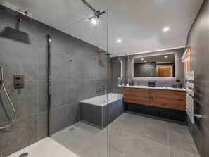 A modern bathroom with a glass-enclosed shower, a standalone bathtub, and a vanity with a mirror.