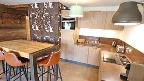 A modern kitchen with a wooden dining table, chairs, and a built-in oven. - Modern apartment, elevator - 6 guests (Les Gets)