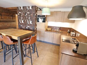 A modern kitchen with a wooden dining table, chairs, and a built-in oven. - Modern apartment, elevator - 6 guests (Les Gets)