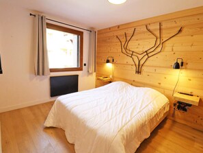 A bedroom with a large bed, a window with curtains, a wall-mounted tree design, and bedside lamps. - Modern apartment, elevator - 6 guests (Les Gets)