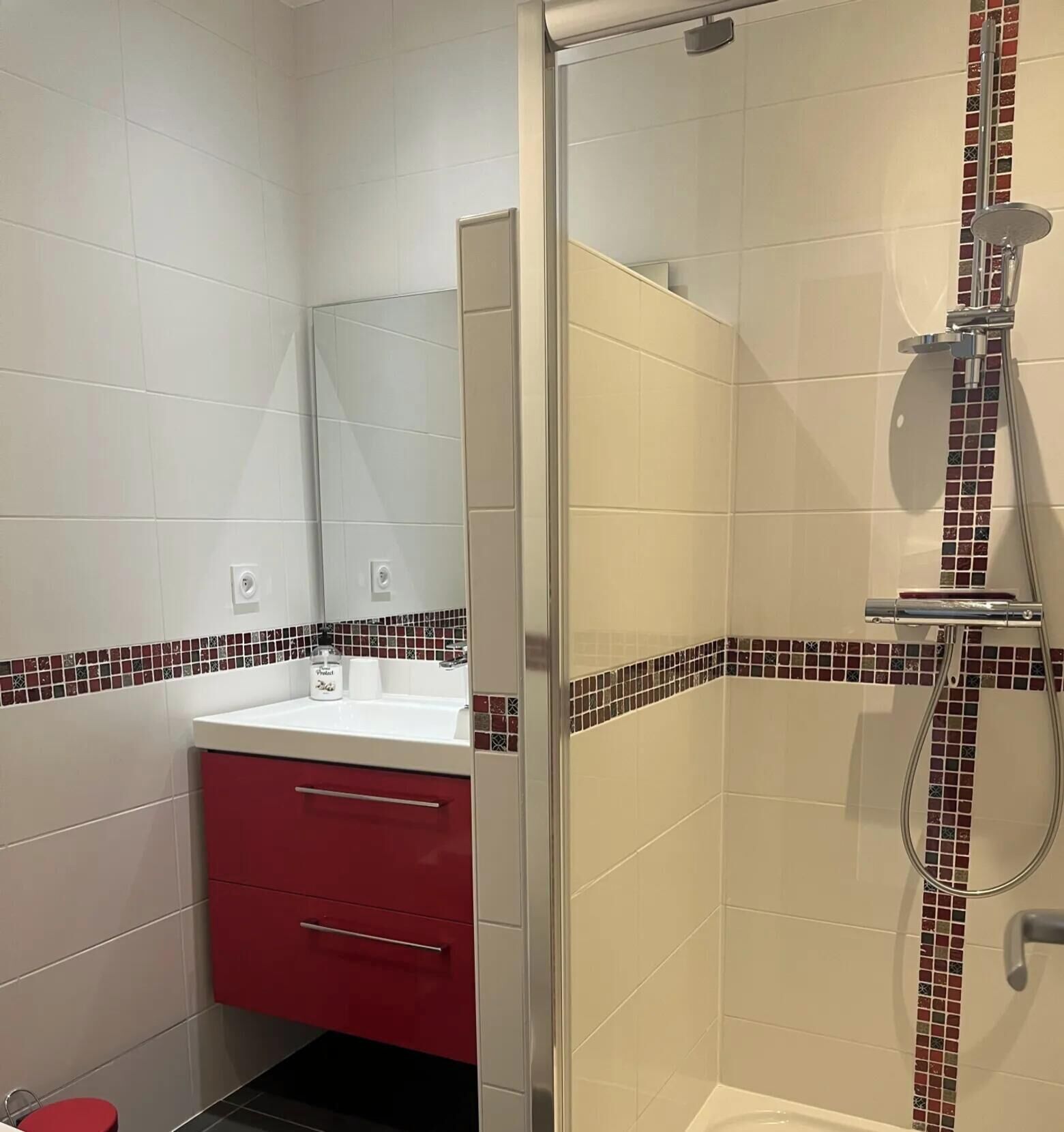Ein Badezimmer mit Dusche, Waschbecken und Spiegel.