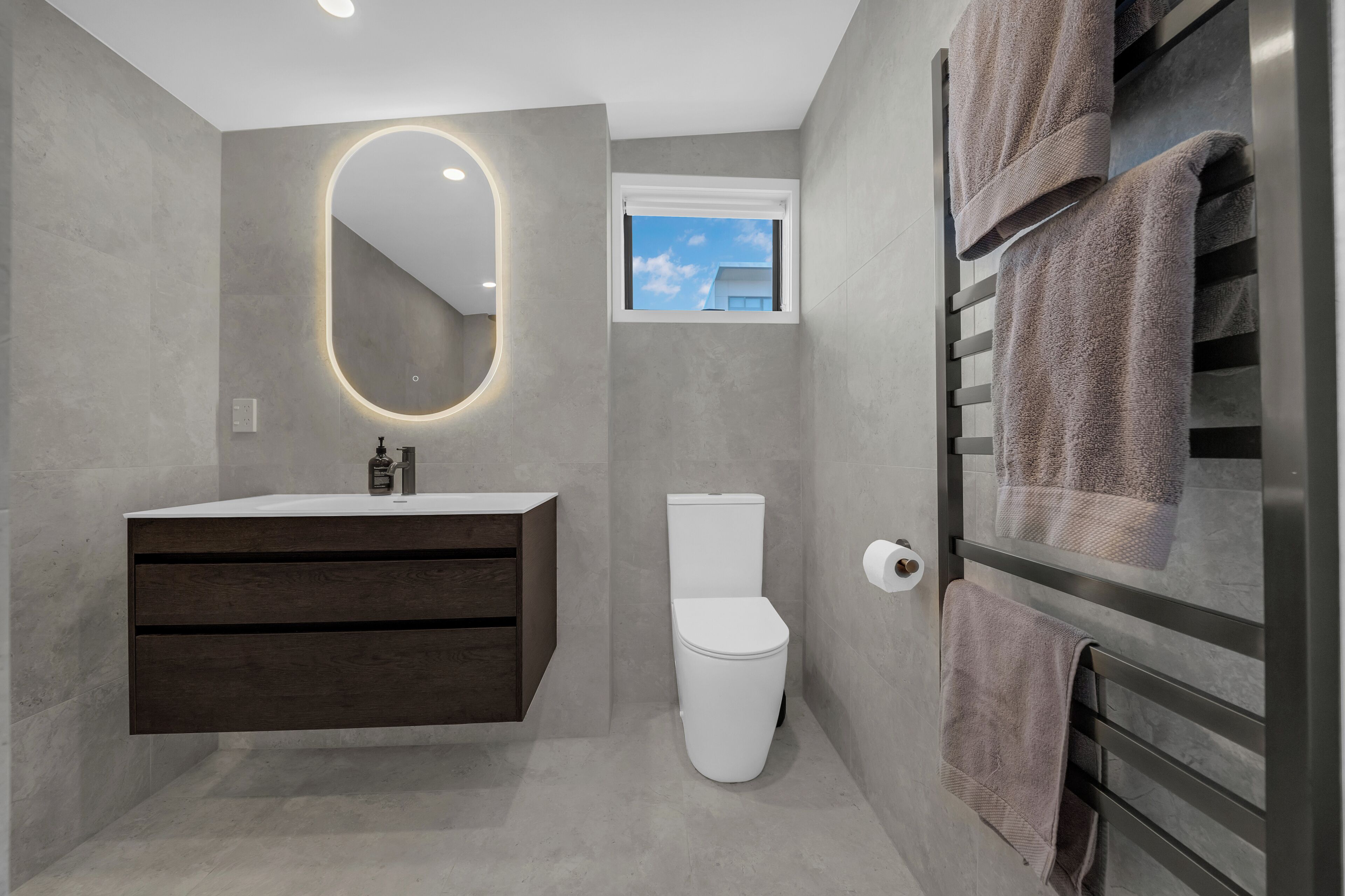 A modern bathroom with a vanity, toilet, and towel rack.