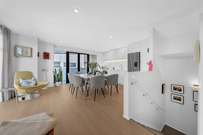 Eine moderne Wohnung mit Essbereich, Küche und Wohnbereich inklusive Sofa und Sessel.