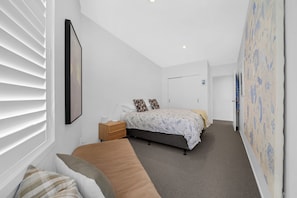 A bedroom with a bed, bedside table, and a window with blinds. - A light-filled Ponsonby townhouse. Open-plan living opens to a sheltered balcony, with a restful queen bedroom and a separate TV lounge to retreat to. Step outside and you're spoilt for choice: Ponsonby Road's cafés, shops and restaurants. (Ponsonby)