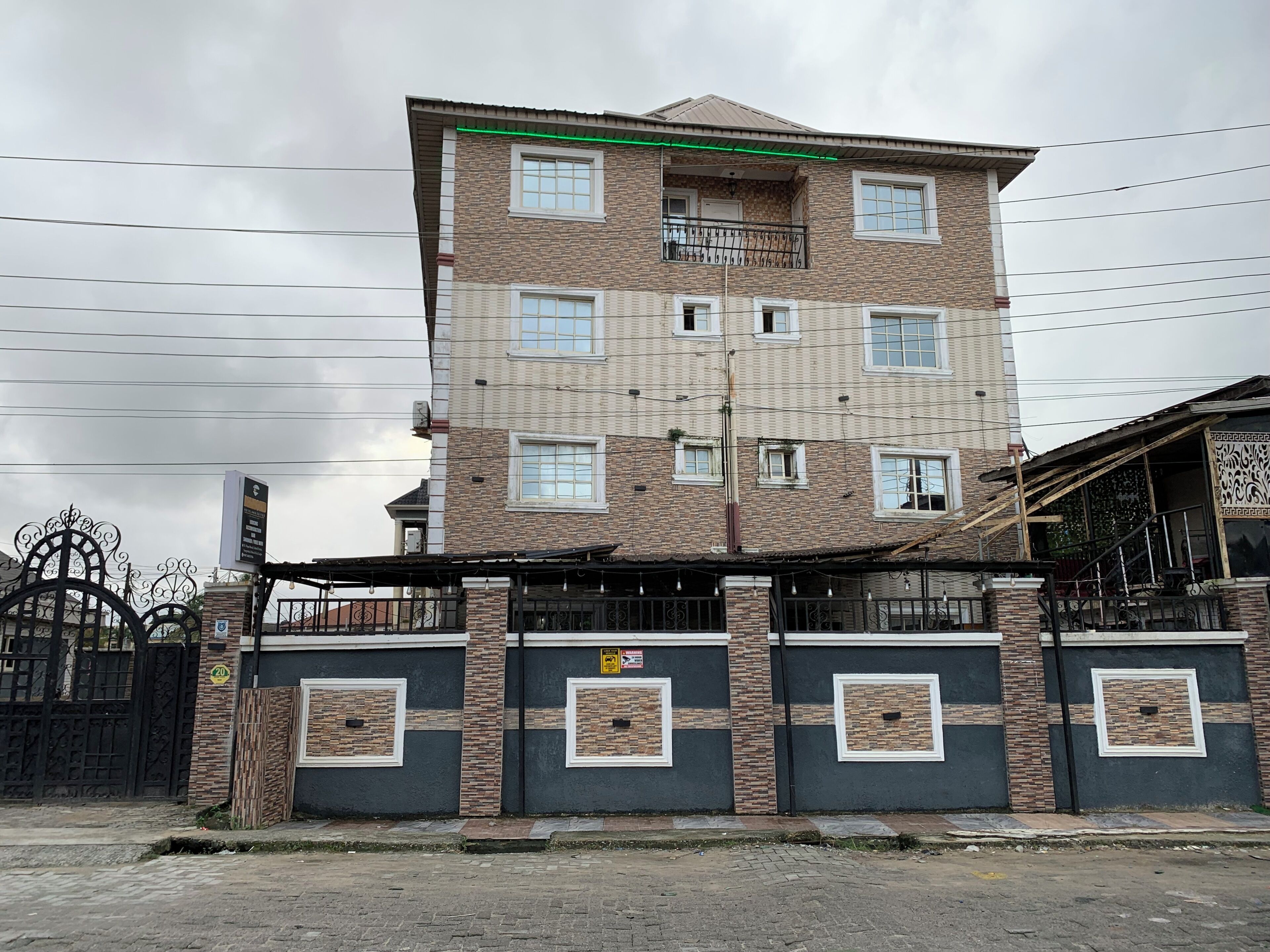 Un edificio de varios pisos con entrada protegida, múltiples ventanales y un balcón.