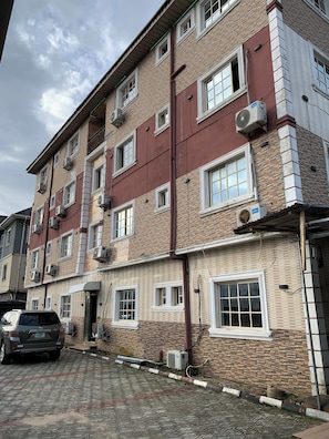 A multi-story building with brick and concrete exterior, multiple windows, and air conditioning units.