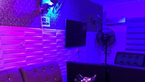 A modern lounge area with a sofa, a coffee table, and a fan. - Diamond Groove Hotel & Suites (Sangotedo)