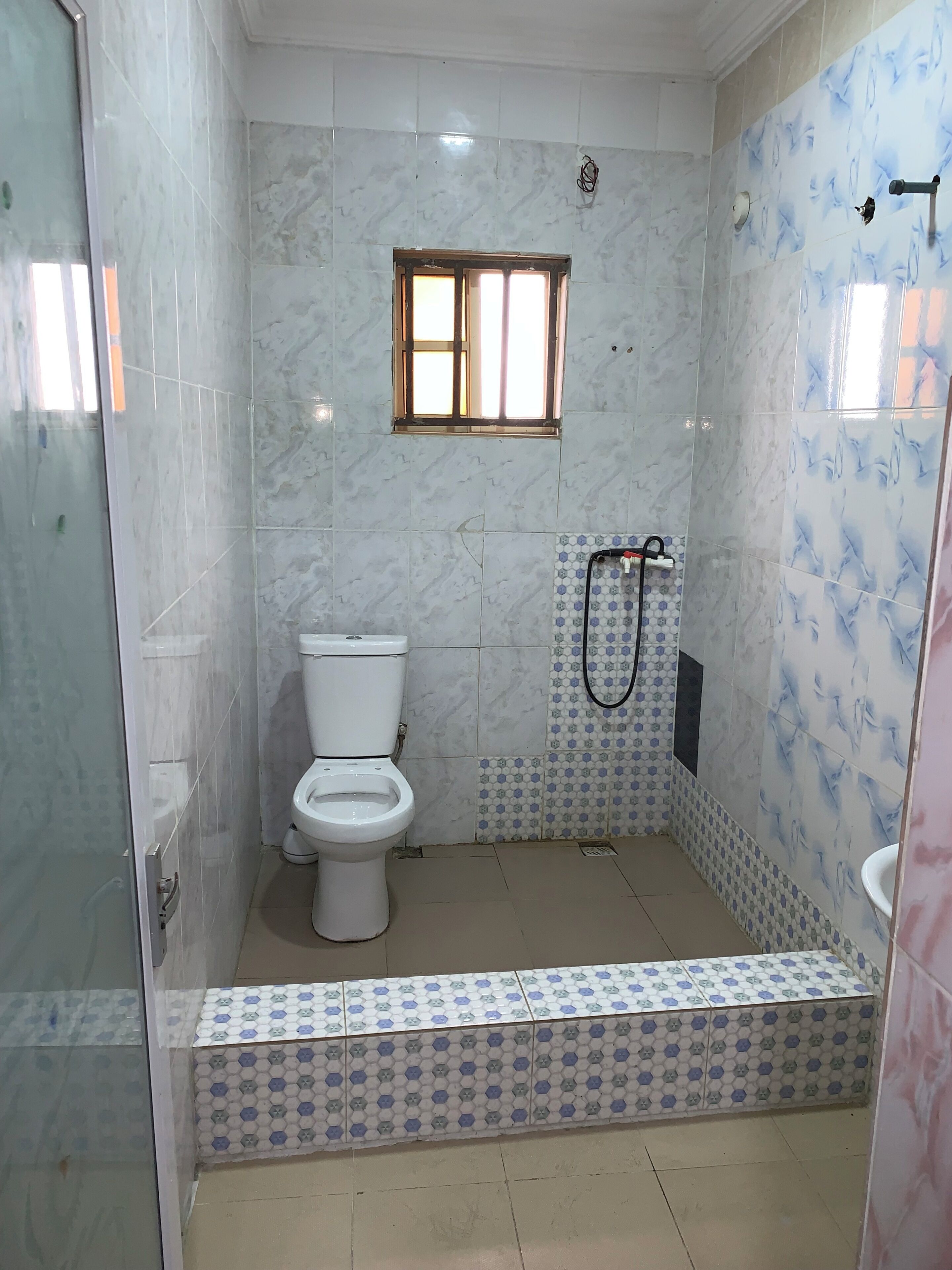 Un baño con inodoro, ducha y ventana.