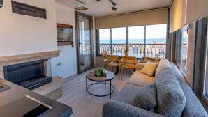 A modern living room with a fireplace, a sofa, and a dining area with chairs. - ARVIA SUITES (Altinova)